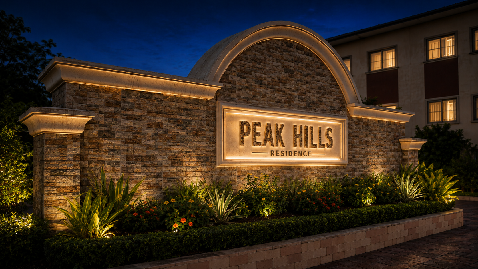 The stone entrance sign of Peak Hills Residence at night, lit from below